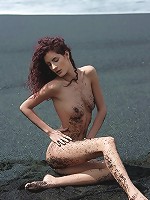 Skiny babe with long legs posing nude on the dark sand and show us her tiny tits and pussy